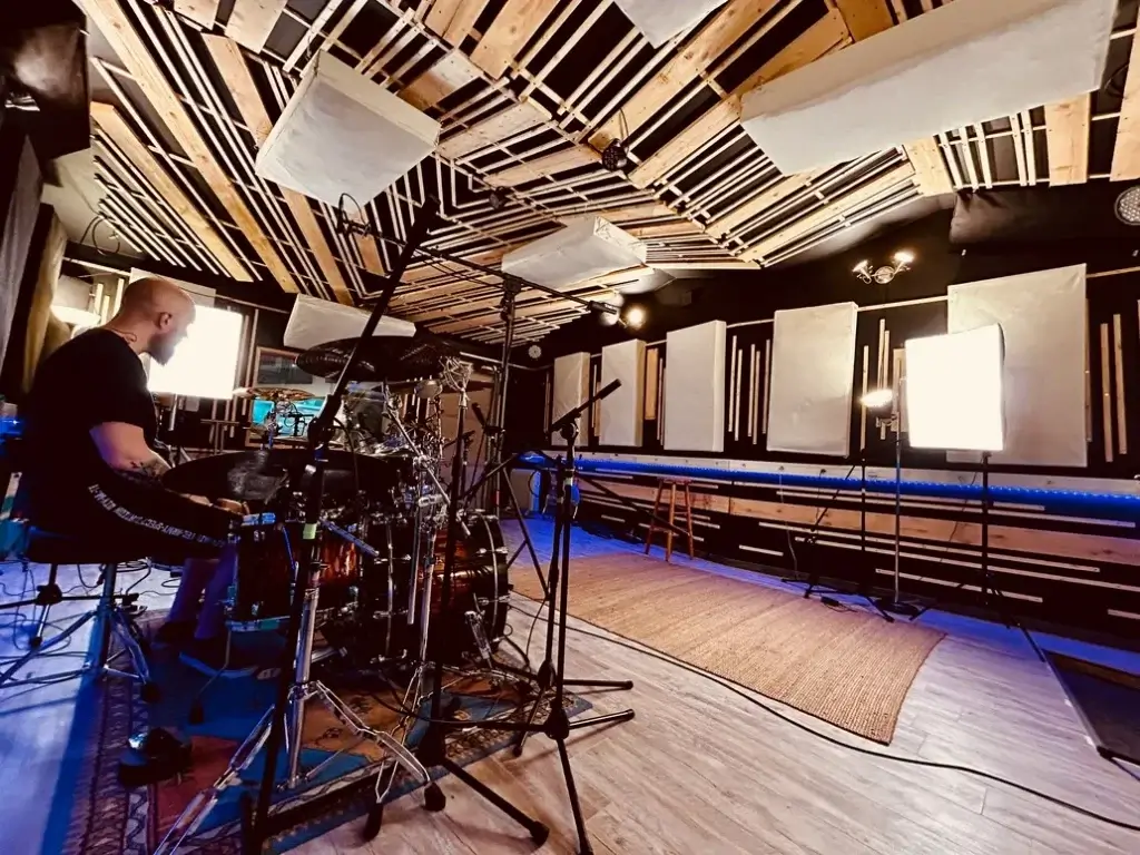 Batteur en session d’enregistrement dans la salle du Sound Up Studio, entouré de micros et d’un traitement acoustique soigné.