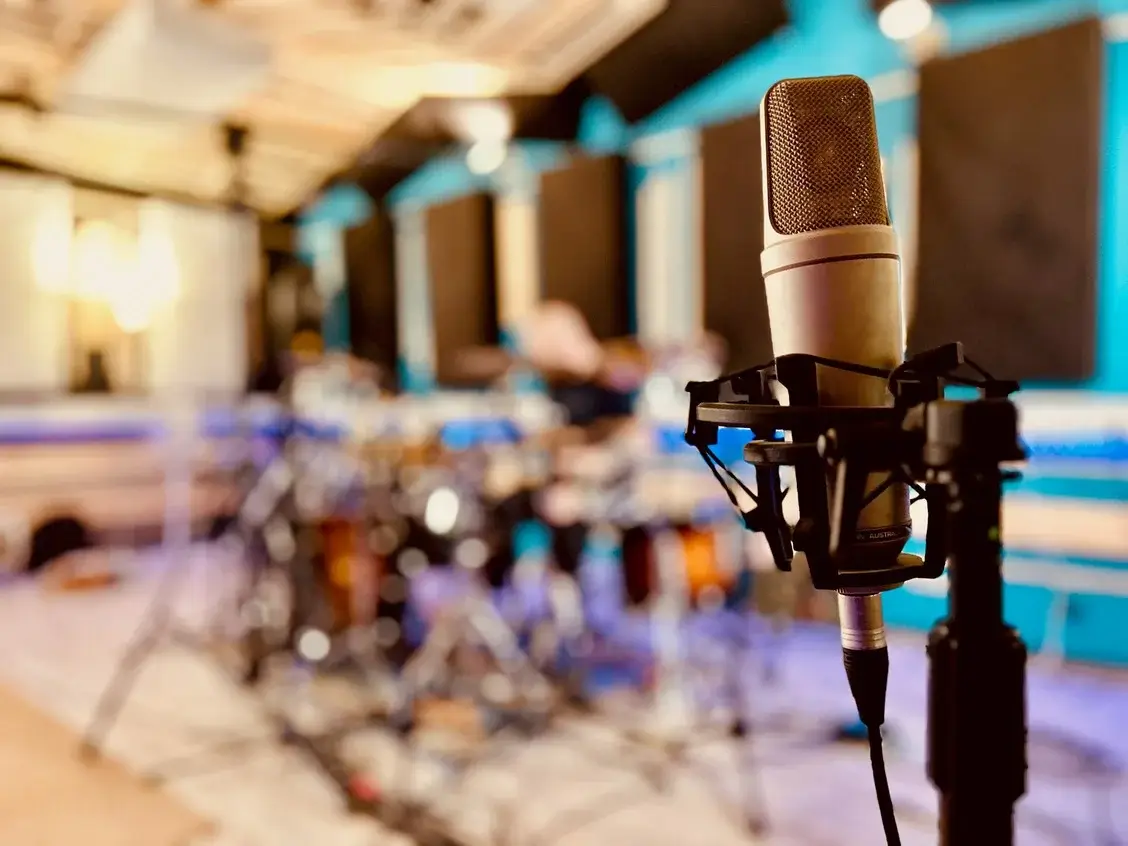 Un micro de studio sur sa suspension, devant une batterie installée dans la salle de prise.